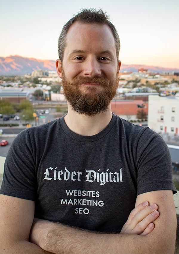 Ron Stauffer smiling and wearing a company shirt that says "Lieder Digital" with downtown Tucson in the background